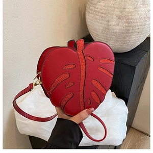Detail of red leaf-shaped shoulder bag featuring glitter veins and matte leather texture