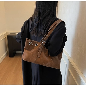 Detailed view of brown vintage shoulder bag with silver eyelets on a fashion model