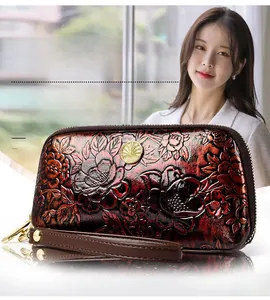 Detail of embossed floral pattern on vintage red leather wristlet with golden hardware