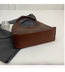 Detail of dark brown woven tote bag featuring soft leather base and intricate pattern