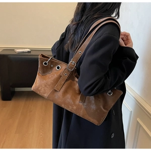 Detail view of a vintage brown leather tote bag with silver eyelets and buckle details