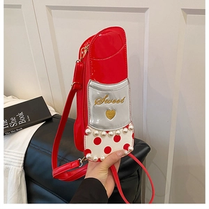 Détail du sac bandoulière rouge en forme de rouge à lèvres avec perles et broderie