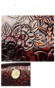 Detail of embossed floral texture and golden hardware on a vintage leather wristlet bag