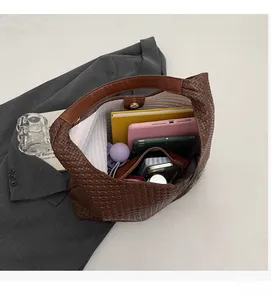 Detail showing the spacious interior of the brown woven tote bag holding a tablet and books