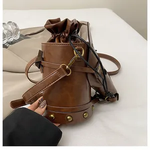 Detail of vintage brown leather bucket bag with gold rivets and drawstring closure