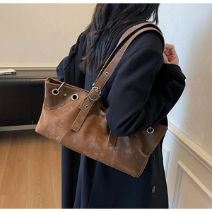 Detail of vintage brown tote bag with silver metallic eyelets and adjustable shoulder strap
