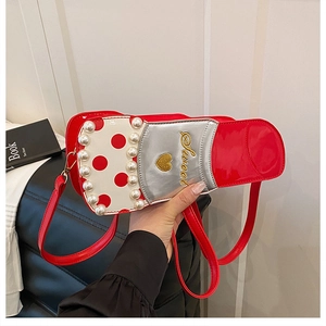 Détail du sac rouge en cuir verni avec pois blancs et accents de perles