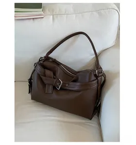 Detail of dark brown lychee leather tote bag with silver zippers on a white sofa