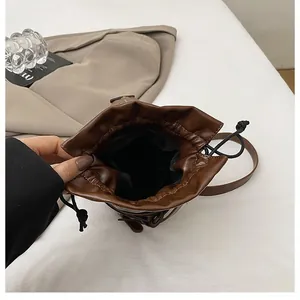 Detail of a brown drawstring bucket bag showing internal black lining and leather texture