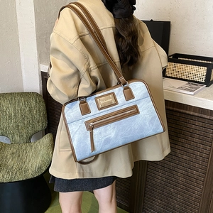 Stylish light blue shoulder bag with brown leather trim shown in a cozy home setting