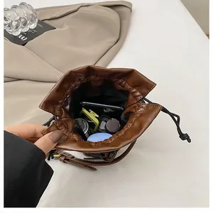Interior view of brown drawstring bucket bag showing storage for phone and cosmetics