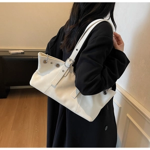 Detail of ivory glossy leather underarm bag with silver eyelets and buckle on shoulder strap