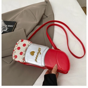 Détail du sac bandoulière rouge en forme de rouge à lèvres avec perles et broderie Sweet