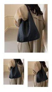 Close-up detail of the woven texture and wide shoulder strap on this black leather tote