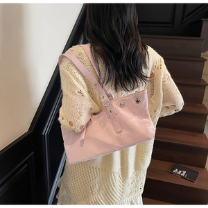Detail of pink faux leather shoulder bag featuring silver metal eyelets and adjustable strap