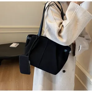 Detail of black suede tote bag featuring adjustable side buckle and detachable coin purse