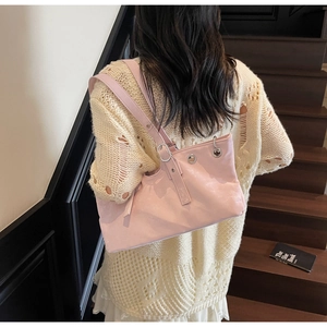 Detail view of pink glossy faux leather shoulder bag with silver eyelets and studs