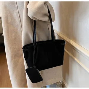 Detail of black faux suede tote bag with small zipper pouch and silver hardware on a model