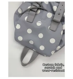 Detail of gray polka dot backpack showing scratch-resistant fabric and leather handle