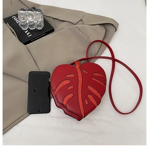 Macro detail of red leaf-shaped PU leather bag with glitter veins and crossbody strap