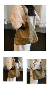 Detail view of large dark green woven hobo bag with wide shoulder strap on model