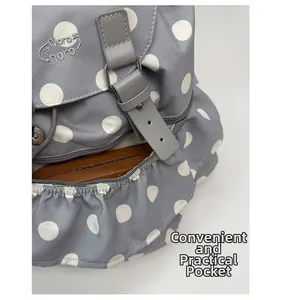 Detail of grey polka dot backpack featuring leather buckle and anti-theft zipper pocket