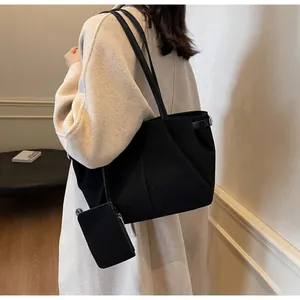 Detail of black suede tote bag with matching detachable pouch and minimalist shoulder strap