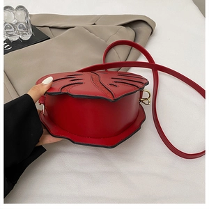 Detail view of red leaf-shaped crossbody bag with gold buckle and elegant metallic finish