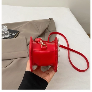 Détail du sac bandoulière rouge avec de grandes perles blanches et des boucles dorées