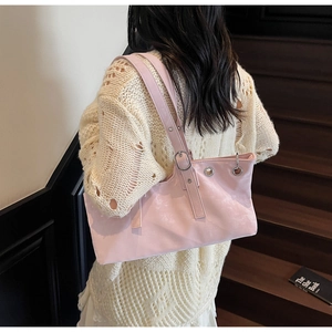 Detail of pink faux leather shoulder bag with silver eyelets and adjustable strap on model