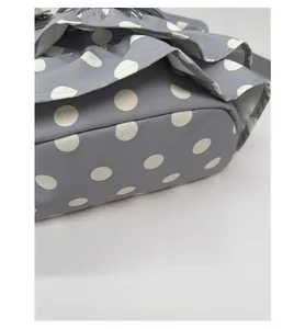 Close-up of gray polka dot backpack showing reinforced base and ruffle edge details