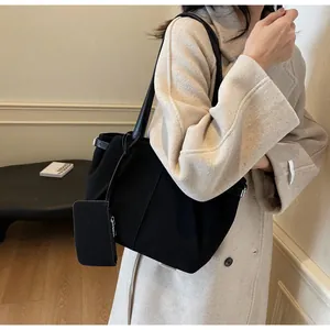 Detailed view of a black tote bag with shoulder straps and a matching zipper pouch