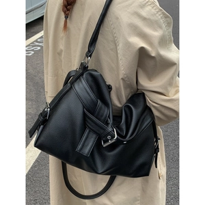 Vintage black lychee leather tote bag with buckle straps worn with a beige trench coat