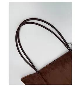Detail of slim shoulder straps with metal ring buckle on brown suede tote bag