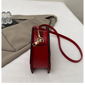 Side view of heart-shaped red PU leather bag with gold metal hooks and red zipper