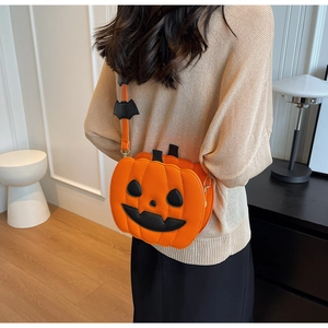Detail of pumpkin crossbody bag with bat charm worn over the shoulder in a home setting