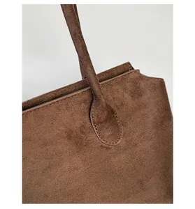 Detailansicht der präzisen Nähte an der braunen Wildleder-Tasche mit Ledergriff-Verbindung