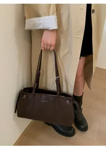 Detail of dark brown leather tote bag showing fine texture and adjustable shoulder strap