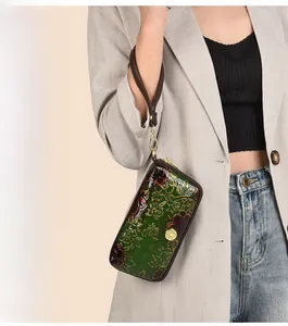 Detail of green 3D embossed leather clutch featuring intricate floral patterns and gold wristlet