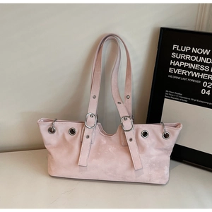 Detail of light pink suede underarm bag with silver grommets and adjustable straps