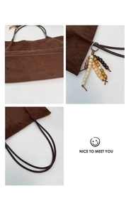 Detail view of dark brown suede tote bag with colorful ethnic bead pendant accessory
