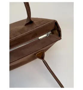 Nahaufnahme des silbernen Reißverschlusses und der braunen Wildlederstruktur der Vintage-Tasche