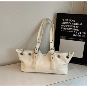 Detail view of cream shoulder bag with silver eyelets and matte leather texture