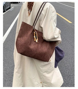 Detail of dark brown suede tote bag with wooden bead charm and long leather straps