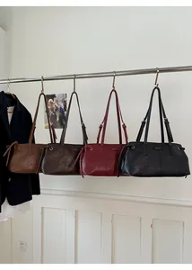 Detail view of stylish leather handbags in brown, burgundy, and black on a minimalist display