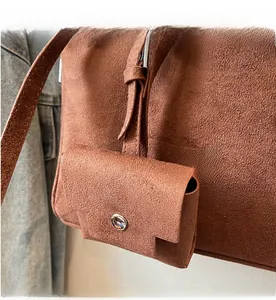 Detail of a brown matte suede shoulder bag featuring a small detachable side pouch with snap