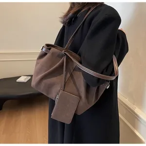 Detail shot of a dark brown suede tote bag featuring a matching mini zipper pouch accessory