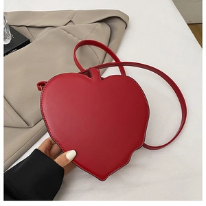 Detail of red heart-shaped shoulder bag in PU leather on a clean white surface