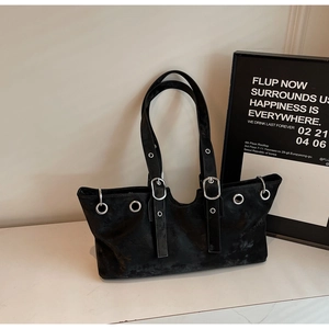 Detail of black matte shoulder bag featuring silver metal eyelets and adjustable buckle straps