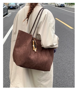 Detail of dark brown faux suede tote bag with wooden bead tassel on a street style model